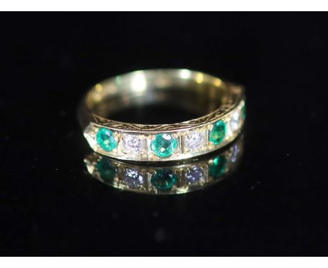   A modern 18ct gold, four stone emerald and three stone diamond set half hoop ring,with carved setting, size O, gross weight