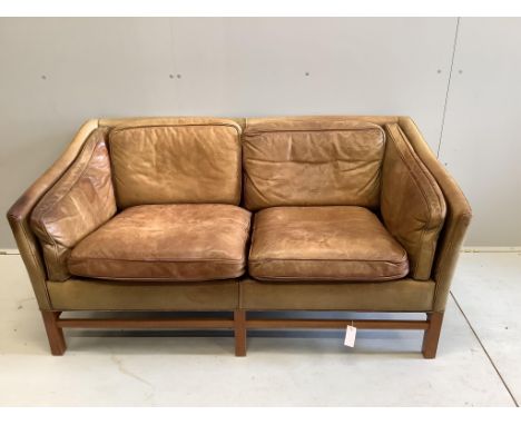 A mid century Danish teak and faded tan leather upholstered two seater settee, width 153cm. Condition - heavily faded from a 