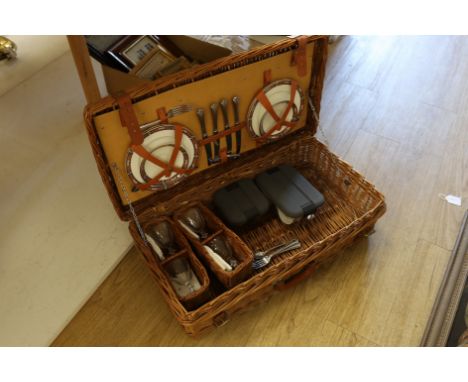 A Harrods wicker picnic hamper for four persons, with Wedgwood plates, cups and saucers, plated cutlery and wine glasses. Con