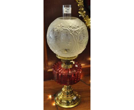 Early 20th Century brass double burner oil lamp with cranberry glass reservoir on brass conical base, frosted repousse glass 