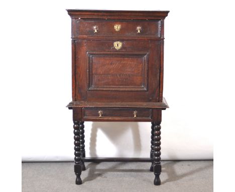 Joined oak cabinet on stand, rectangular top, moulded cornice above a frieze drawer, fall front section enclosing eight drawe