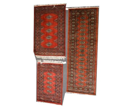 Three similar rugs/ runners, Bokhara style with single rows of guls, enclosed with geometric borders, runner 195cm x 65cm; 13