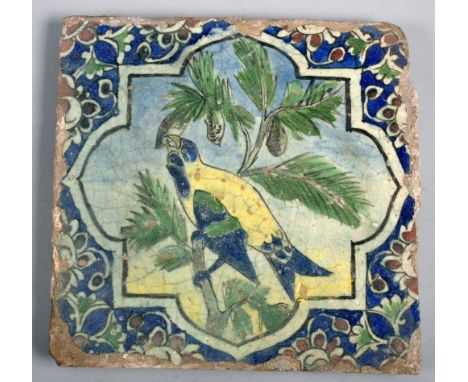 A late 18c/early 19c Persian tile painted with a parrot eating fruit in a tree, 11.5in x 11.5in.