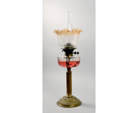 A late Victorian oil lamp with a brass column on a circular dome base with a facet cut font, together with a replacement funn