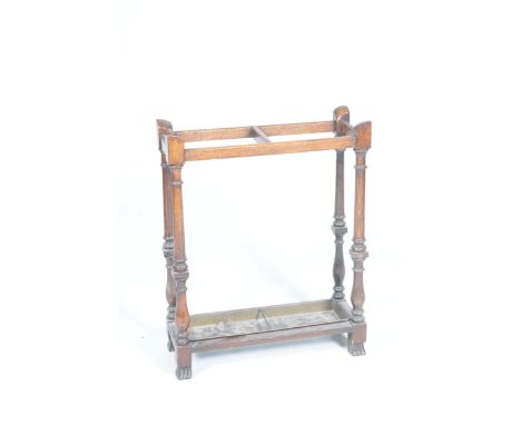 A 1920's oak stick stand With twin compartments raised on ring turned tapering supports with a fitted rectangular metal tray 