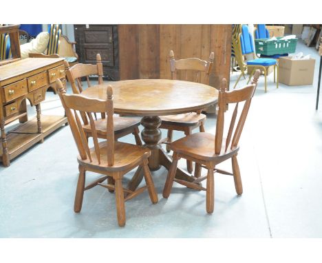 A modern oak circular kitchen table and four stick back chairs.