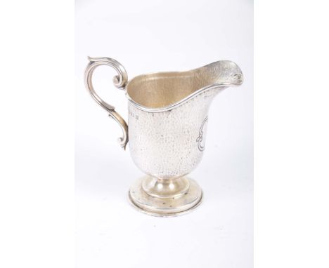 A silver helmet shaped cream jugWith a scroll handle vacant cartouche raised on a stepped circular plinth base Birmingham 190