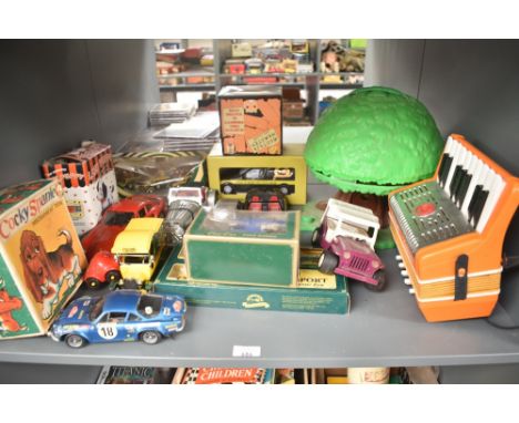 A shelf of mixed toys including Modern Die-casts, Alps Cocky Spaniel Mechanical Toy boxed, plastic Treehouse with contents et