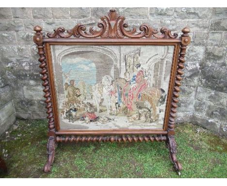 A large 19th century tapestry fire screen, with carved top and raised on barley twist supports, the tapestry depicting figure