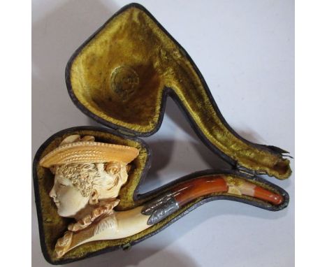 A cased Meerschaum pipe, carved with a woman's head, wearing a hat
