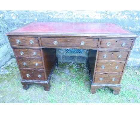 A mahogany desk, fitted with one long drawer, flanked by two short drawers over two pedestals of three drawers, raised on bra