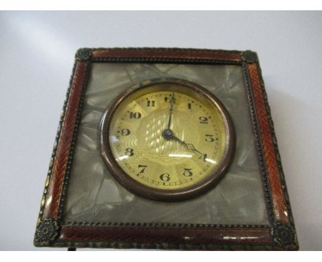 An Art Deco travelling clock, of square form, decorated with an enamel border and flowerhead corners, diameter 3ins
