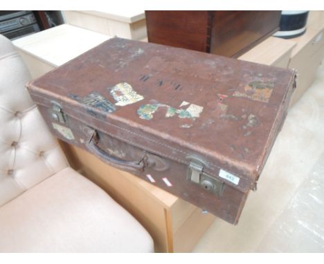 A vintage leather suitcase bearing travel labels