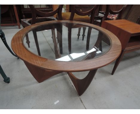 A vintage teak or sapele circular coffee table with glass top