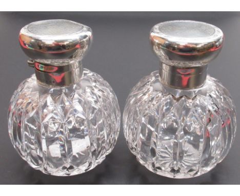 Pair of Geo.V hallmarked silver topped cut glass scent bottles, hinged covers with engine turned and floral decoration on sta
