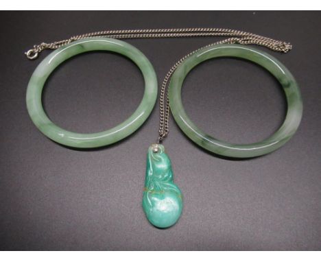 Pair of jade bangles, D7.4cm, and a carved jade pendant in the form of fruit (A/F) on white metal chain, L60cm (3) 