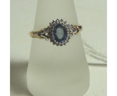 A ladies 9ct gold dress ring, set with a central faceted blue topaz with a surround of tiny diamonds.  Size R.  