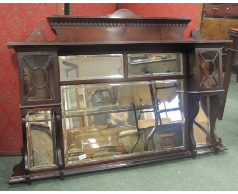 An Edwardian mahogany overmantel mirror with bevelled glass panels, having upper shelf with two small cupboards enclosed with