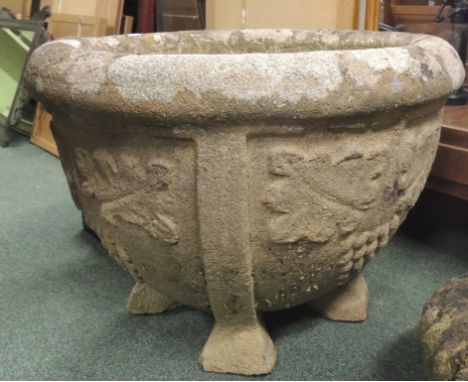 A large circular stone planter with fruiting vine decoration and on low supports 58cms diam 43cms high