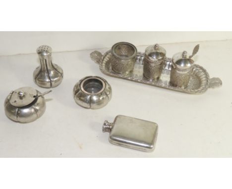 An Indian silver metal, three piece cruet set on an oval tray, embossed stylized foliate decoration,another three piece cruet