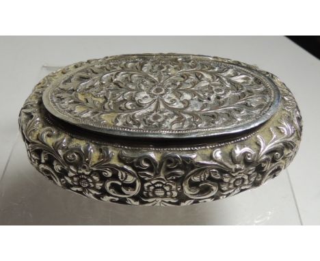 An early 20th Century, Indian white metal oval snuff/tobacco box.  All over beaten and repousee floral decoration, with hinge