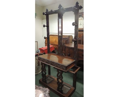 A Victorian carved oak hall stand, the back with inset mirror and original turned wood hangers, the base having hinged top an