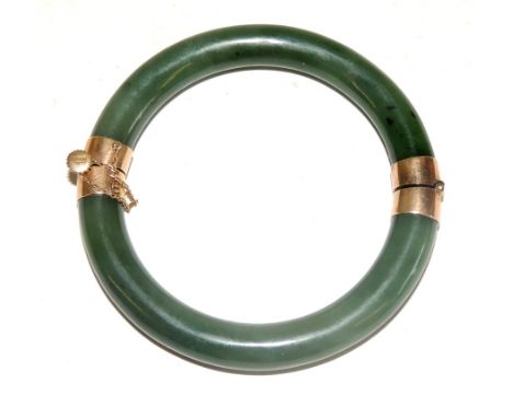 A hinged Jade bracelet with 14ct gold mounts, screw clasp and safety chain.