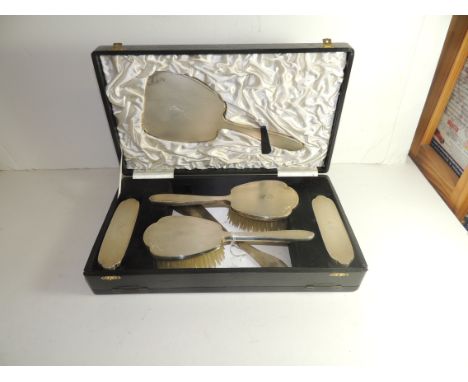 A cased Indian white metal dressing table set, comprising hand mirror, 2 hairbrushes, 2 clothes brushes and a non matching sh