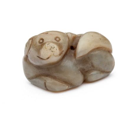 A CHINESE CELADON JADE DOG, QING DYNASTY (1644-1911) carved recumbent with the head turned sharply to the left and the tail s