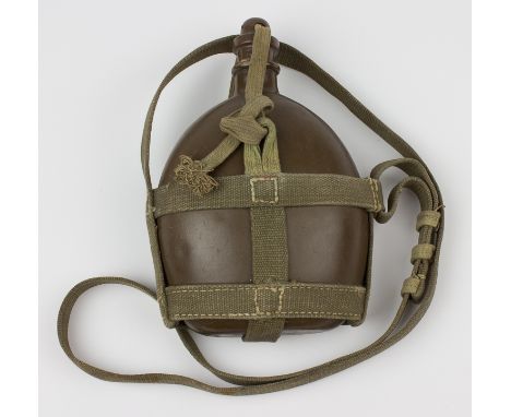 JAPANESE ARMY CANTEENTin canteen, approx. 7 3/4" x 5 3/4", painted brownish-green, secured in an olive-green webbing harness.