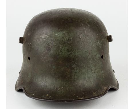 SHRAPNEL-STRUCK GERMAN M1916/1917 HELMETA striking relic of the carnage of World War I, a German M1916/1917 "Stahlhelm"-style