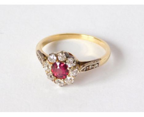 DRESS RING. A ruby & diamond cluster dress ring, with diamond set shoulders, set in unstamped yellow metal, probably 18ct. go