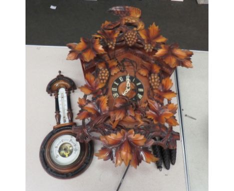 A German cuckoo clock with grape and vine detail. A carved barometer with thermometer dial (2) 