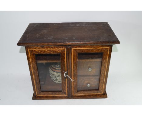 Late 19th century oak smokers cabinet with double glazed doors opening to an interior with two drawers and a stoneware tobacc