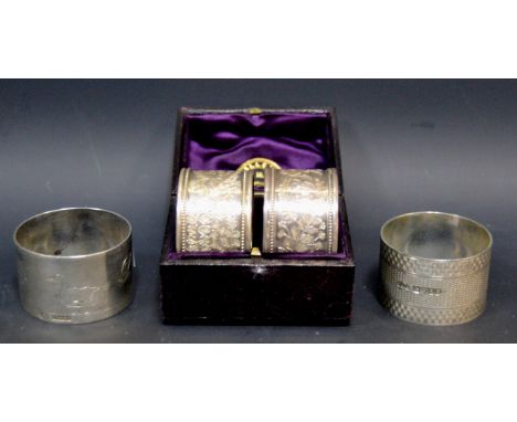 A pair of Victorian silver napkin rings, profusely hand chased with a foliate motif, inscribed with the initials RR, dated 18