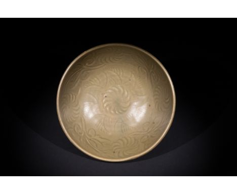 A Chinese Celadon-Glazed Bowl with Incised Floral Motifs.A shallow ceramic bowl with a soft celadon glaze, featuring an incis
