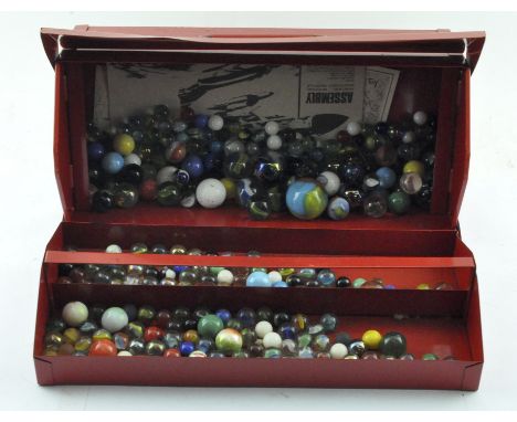 A red metal toolbox containing a large selection of glass marbles, various colours and designs