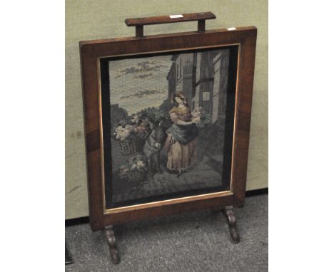 A mahogany and tapestry fire screen, 20th century, depictting a lady flower seller, 80 cm high x 56 cm wide