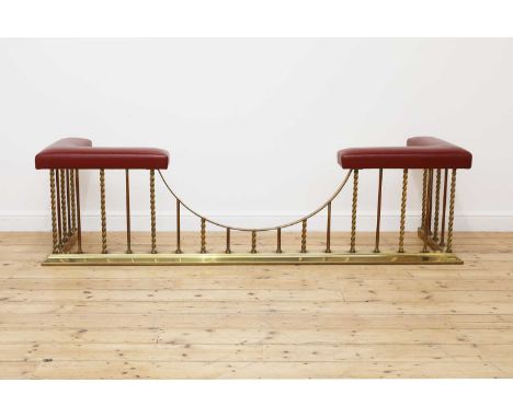 A large brass club fender,20th century, the red leather upholstered seat raised on twisted brass supports, 225cm wide64cm dee