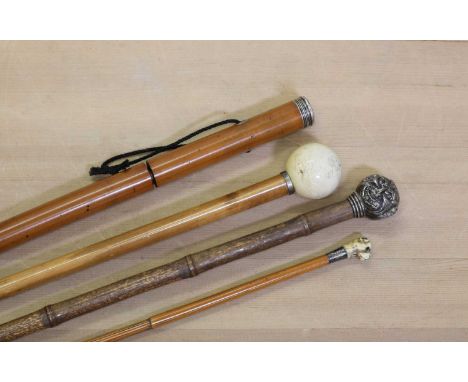 A group of four walking sticks,to include a malacca sword stick, with white metal mounts,85cm long,a bamboo stick, with a sil