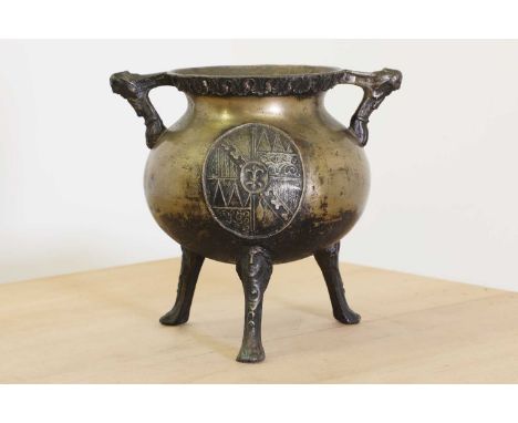 A cast brass tripod cauldron,in 16th century style, both handles with masks, and the ovoid body of the cauldron with an armor