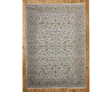 A Persian wool carpet,mid-20th century, Kashan, with a pale green blue ground and decorated with scrolling foliate and vine d