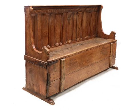 An elm settle bed,18th century and later, the seven-panelled back over a base with hinged seat, enclosing a cot bed within,19