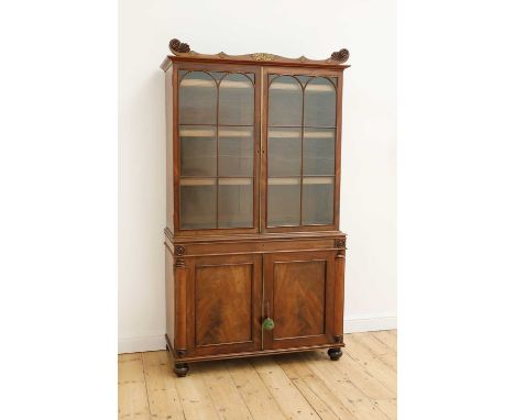 A Regency mahogany bookcase,the scrolled cornice with applied gilt-metal mounts over two astragal-glazed doors enclosing two 