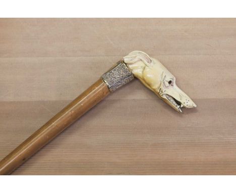 A Victorian malacca walking stick,the malacca handle carved as a dog's head with glass eyes, over an embossed yellow metal co