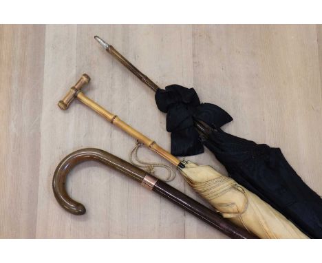 Two parasols and an umbrella stick,one parasol with a bamboo handle by Gauntlet, one with a white metal sphinx-like handle, t