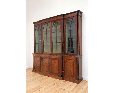 A George III mahogany breakfront bookcase,early 19th century, the moulded cornice above lancet-glazed doors punctuated with r