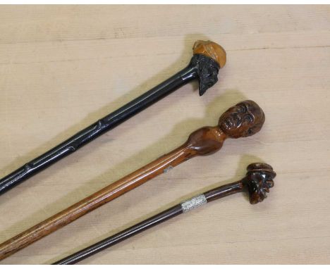 Three walking sticks with carved head handles, comprising: one hardwood example, with safety cord eyelets,86cm long,a small h