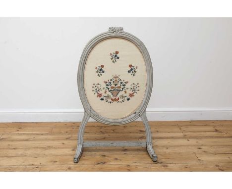 A grey-painted and needlework fire screen,19th century, French, the needlework later, with a foliate carved crest over a moul