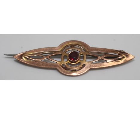 A late Victorian ruby set bar brooch, yellow metal, pierced body and set with a single faceted stone, fitted with a C clasp, 